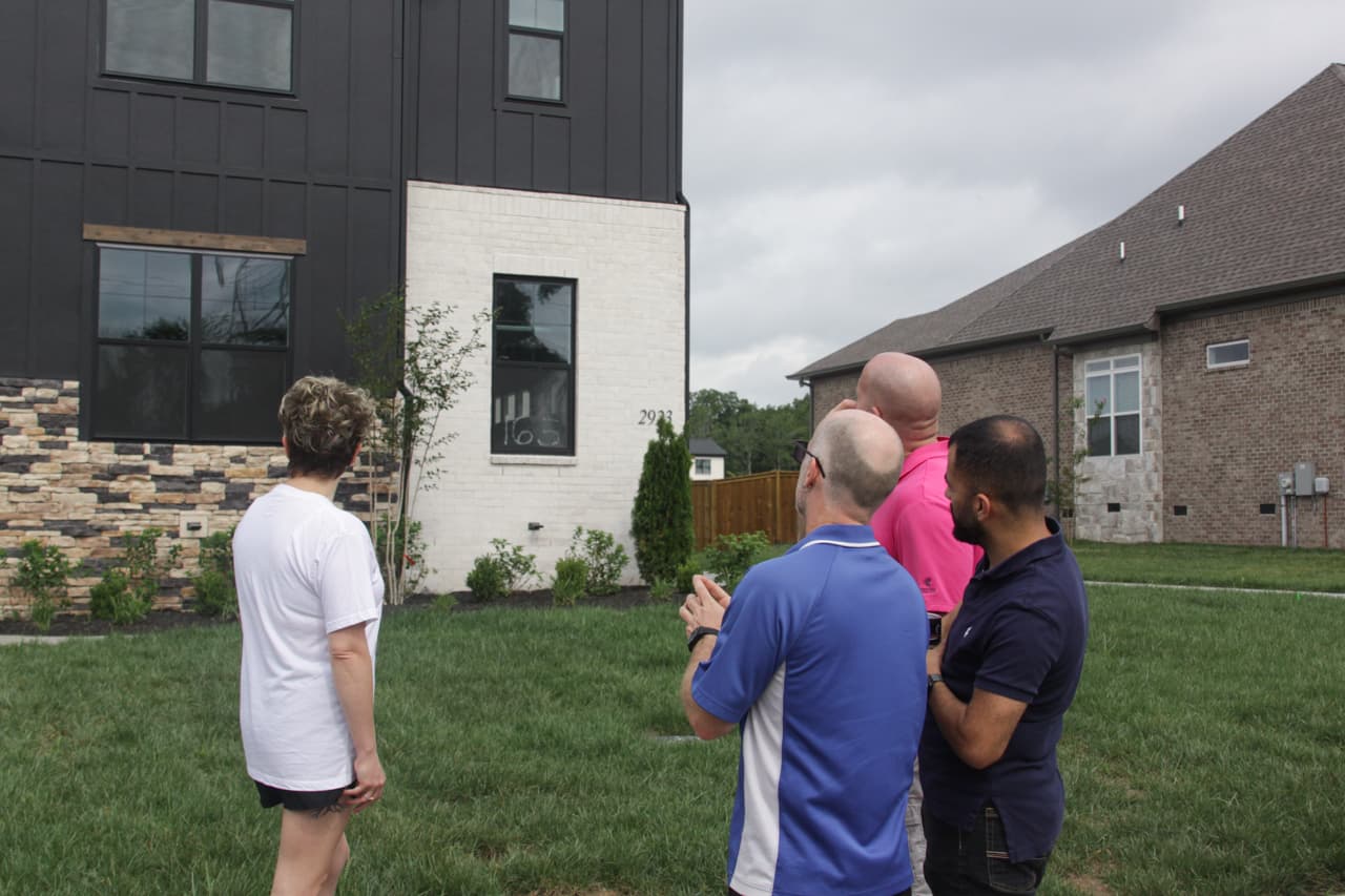 Home inspector reviewing exterior details of a newly constructed home with clients during a new construction inspection