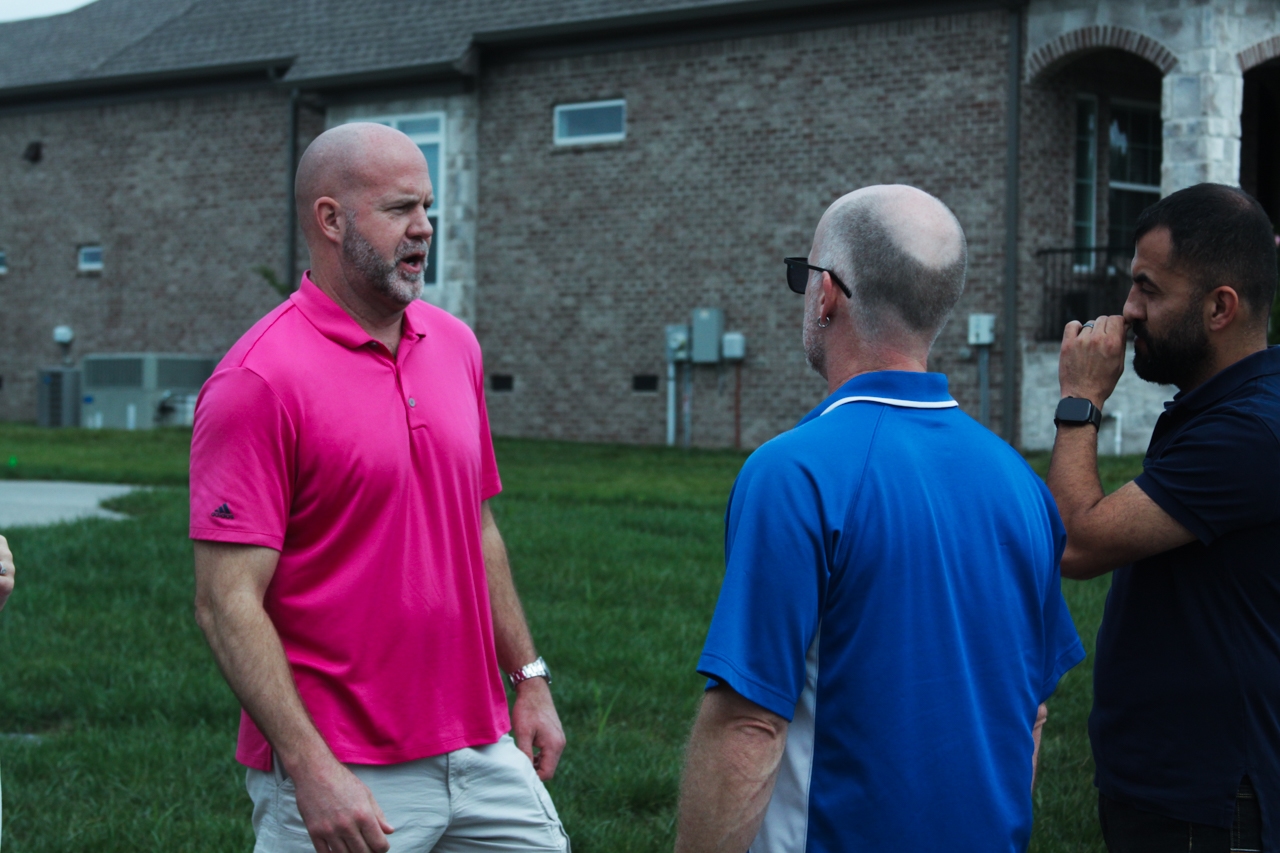 Home inspector discussing inspection details with clients outside a residential property during an on-site home inspection